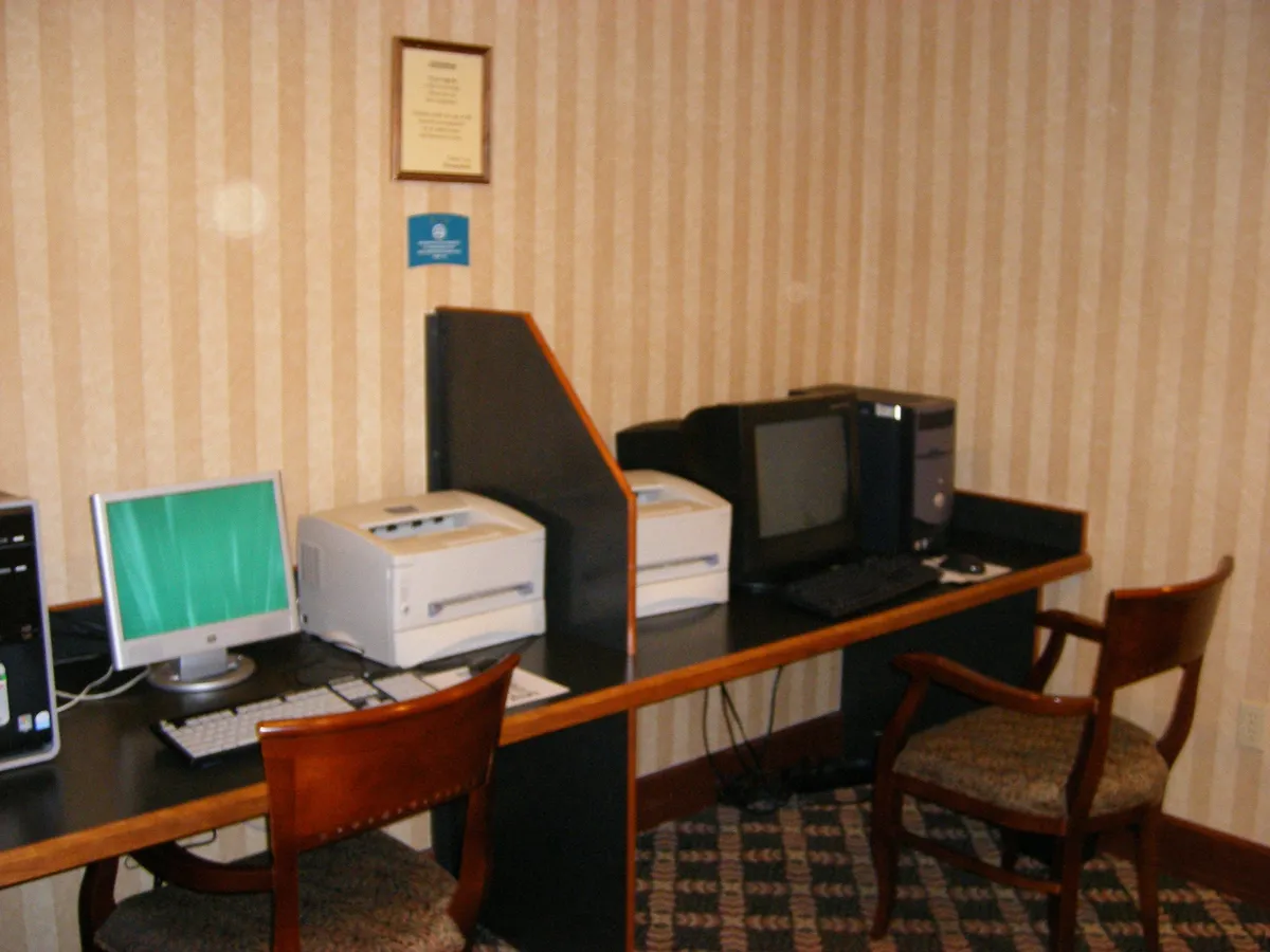 A modern business center with computers, printers, and comfortable seating offers a practical space for business work, printing, and internet browsing. The setup is efficient and inviting, ideal for professionals needing a convenient workspace.